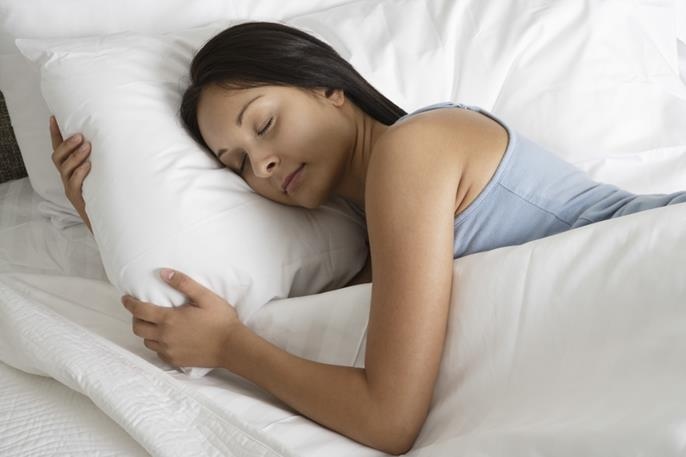 Woman sleeping on her side with her head elevated to help reduce stuffy nose at night.