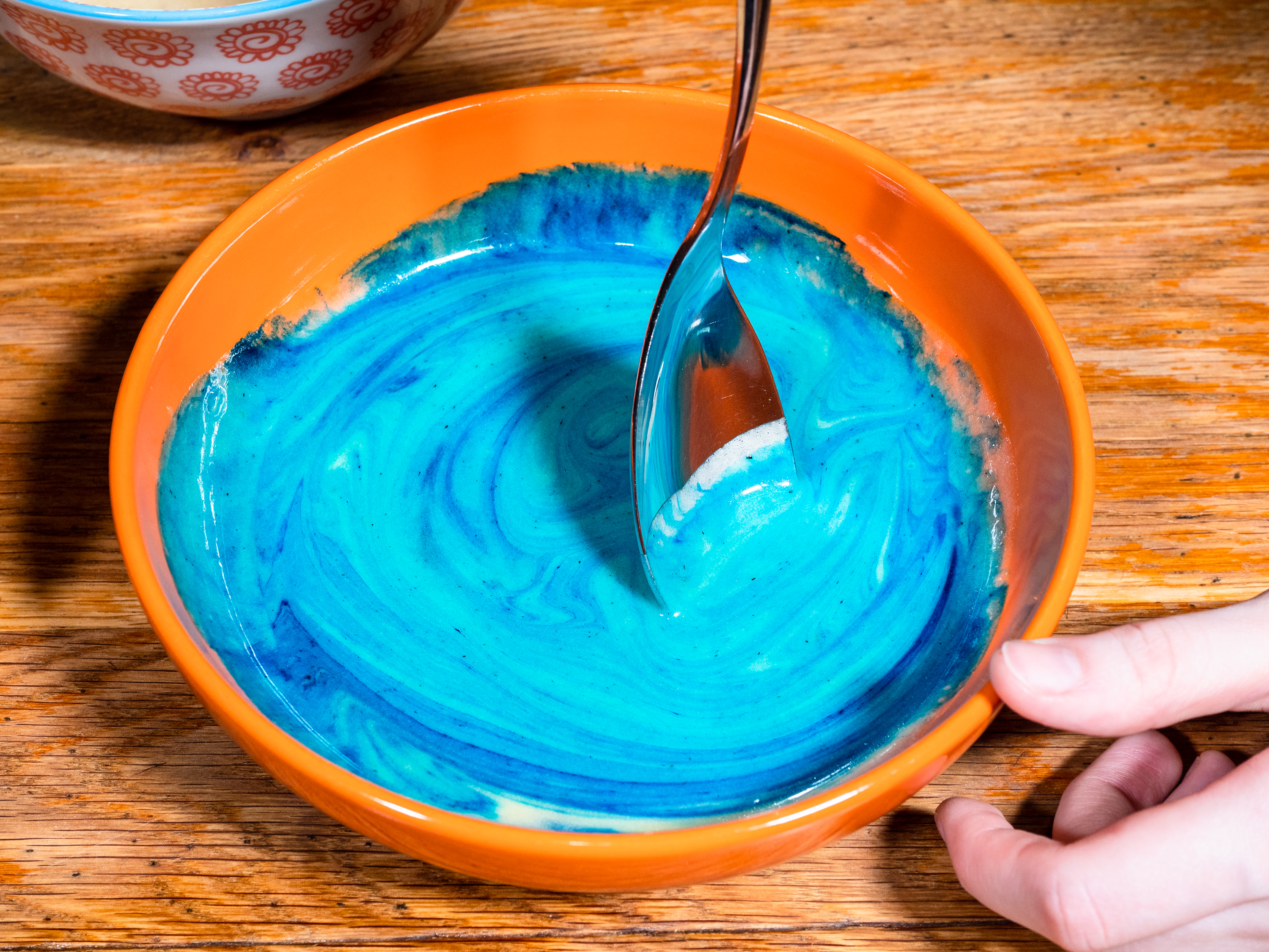 mixing baking soda with blue food coloring in bowl to make paint