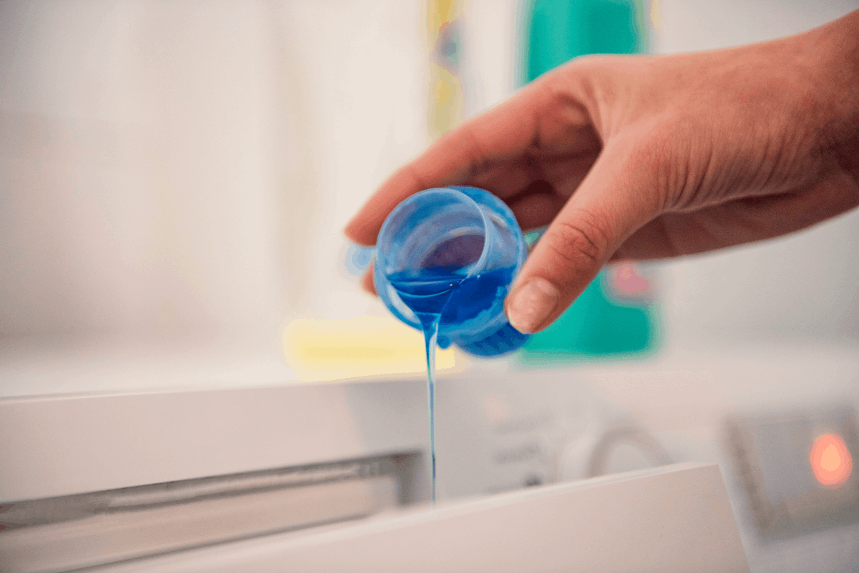 woman pouring Arm and Hammer liquid laundry detergent into washing machine