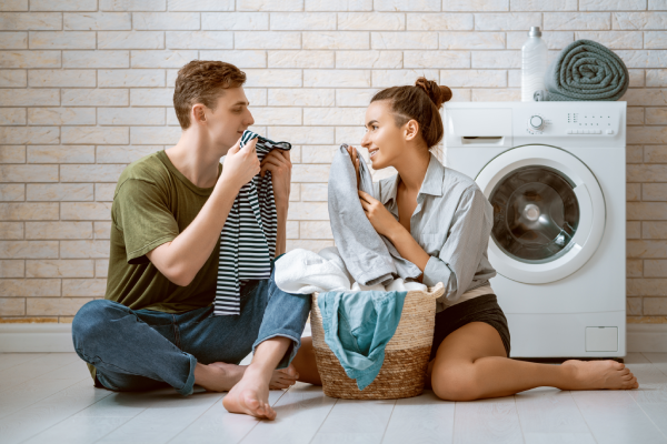 a couple in front of the dryer enjoys the smell of their clean laundry items