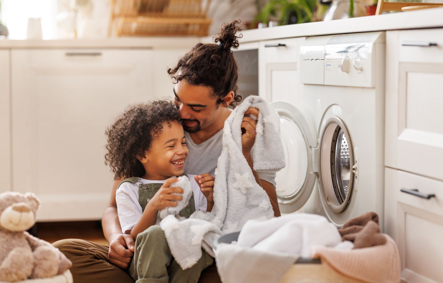 Father and son cuddling while loading clothes into the washer