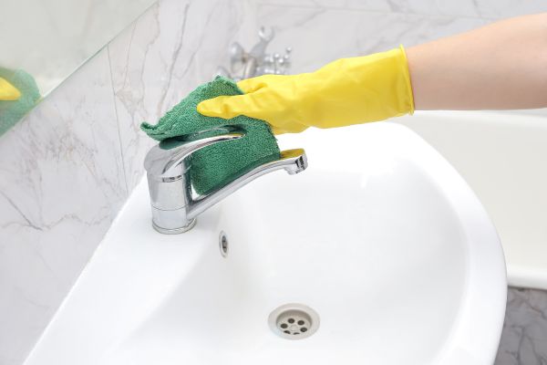 Maid wiping down bathroom faucet with a solution of Arm & Hammer Super Washing Soda.