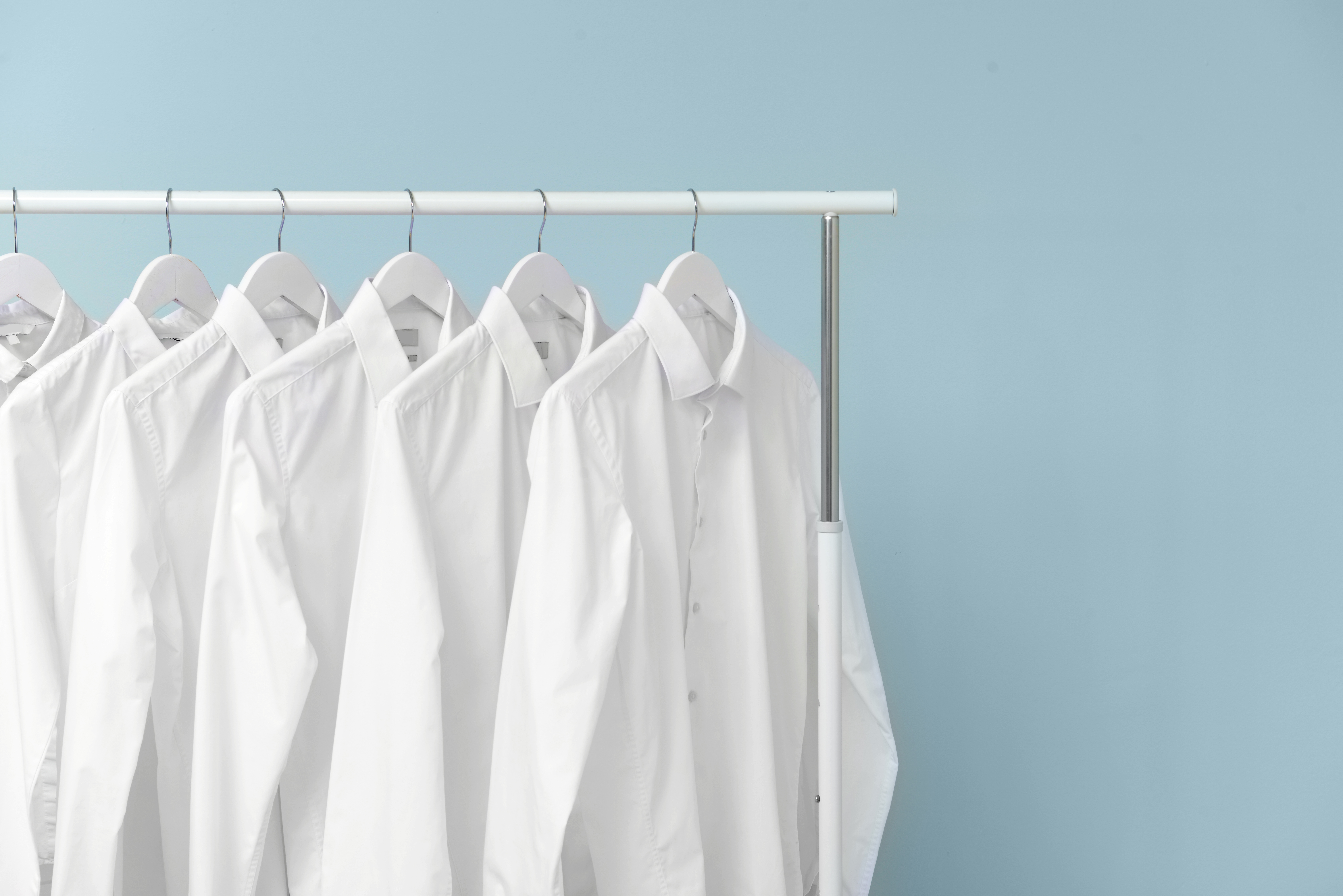 White cotton shirts hanging on clothes rack
