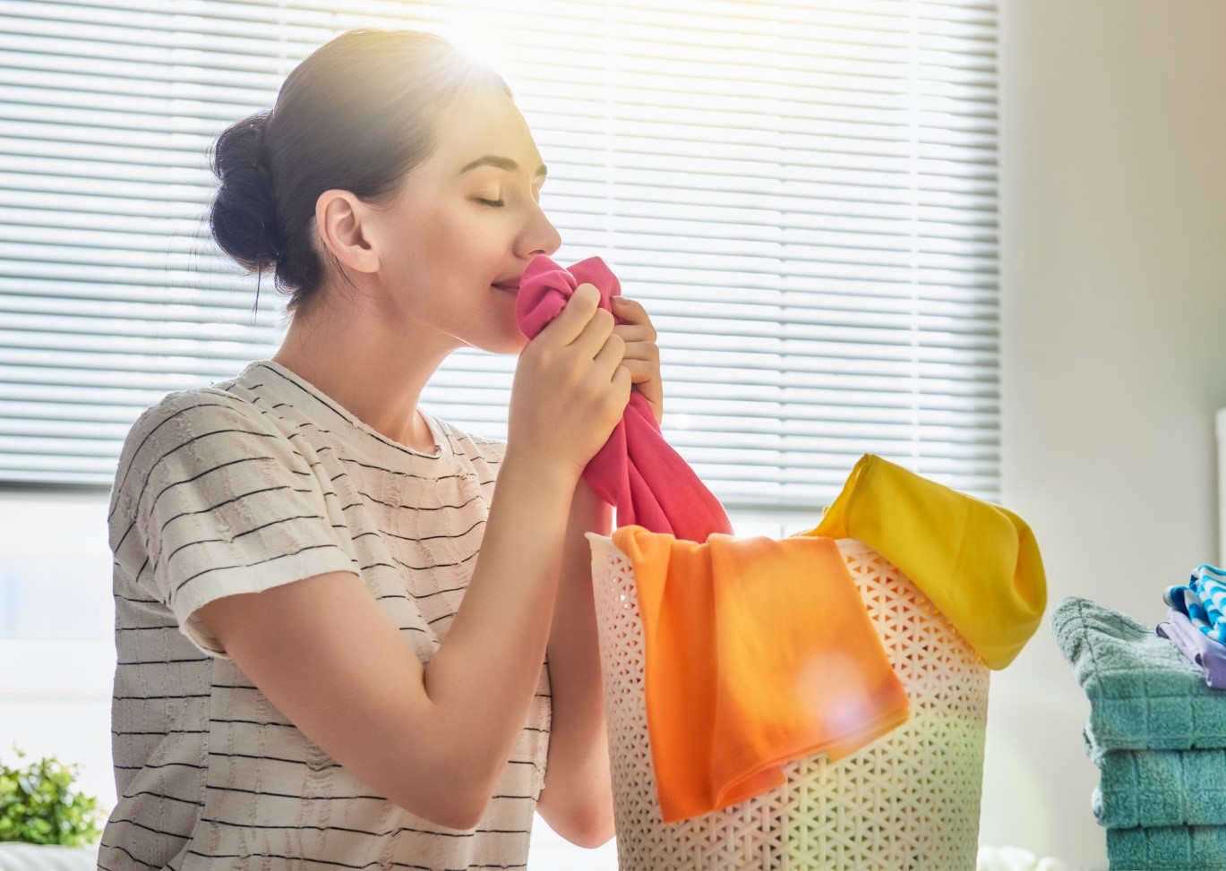 woman smelling fabric softener on clean clothes
