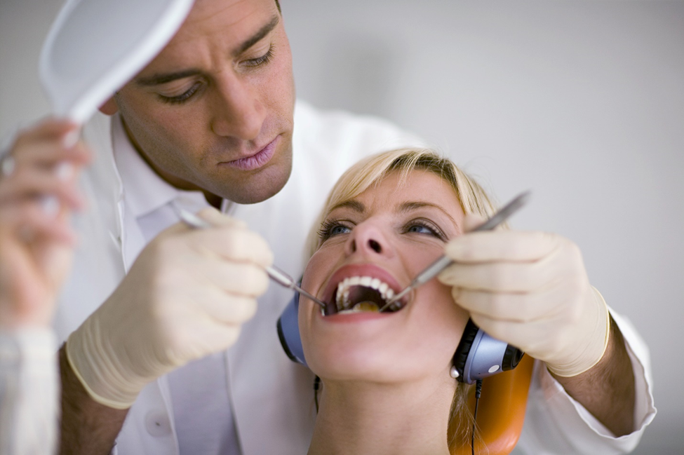 Dentist examining patients mouth with dentist tools