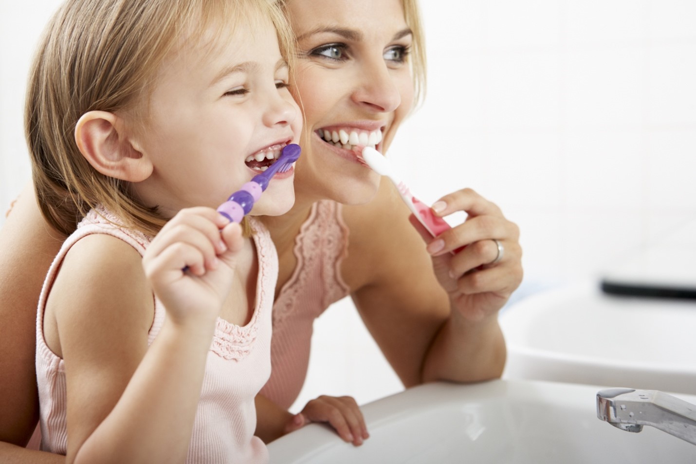 Mother and daughter using their favorite baking soda toothpaste to brush their teeth