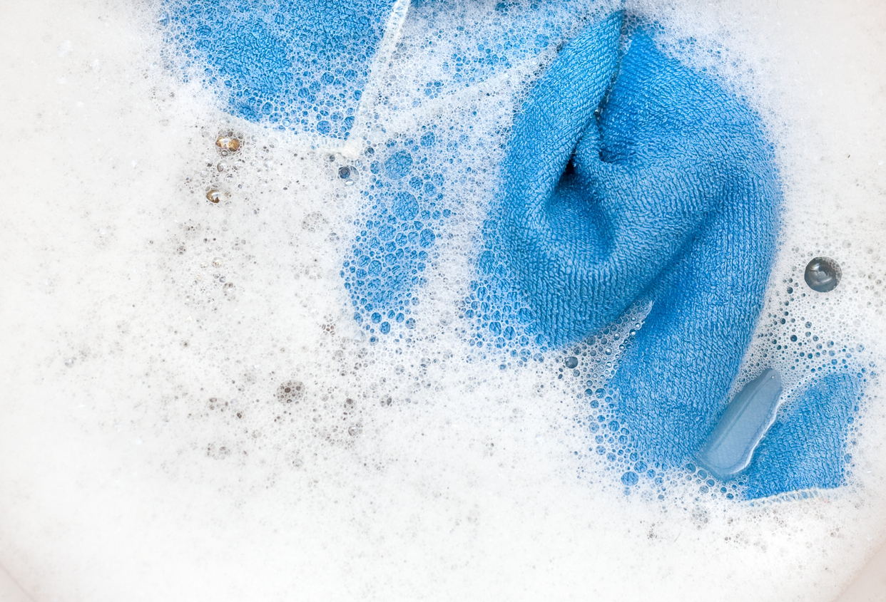 Laundry detergent working to clean clothes in soapy water.