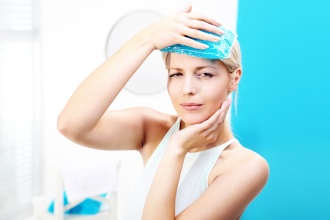 Woman with sinus headache and toothache holds cold compress to her head.